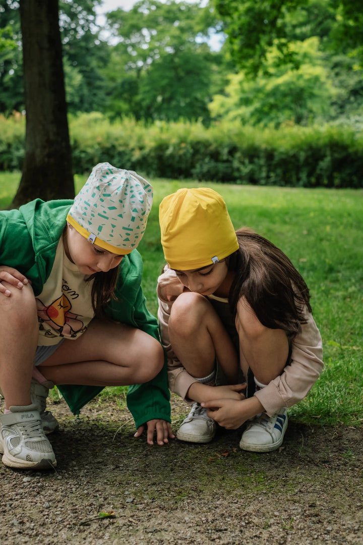 Two girls wearing Breeze organic cotton reversible beanies exploring together