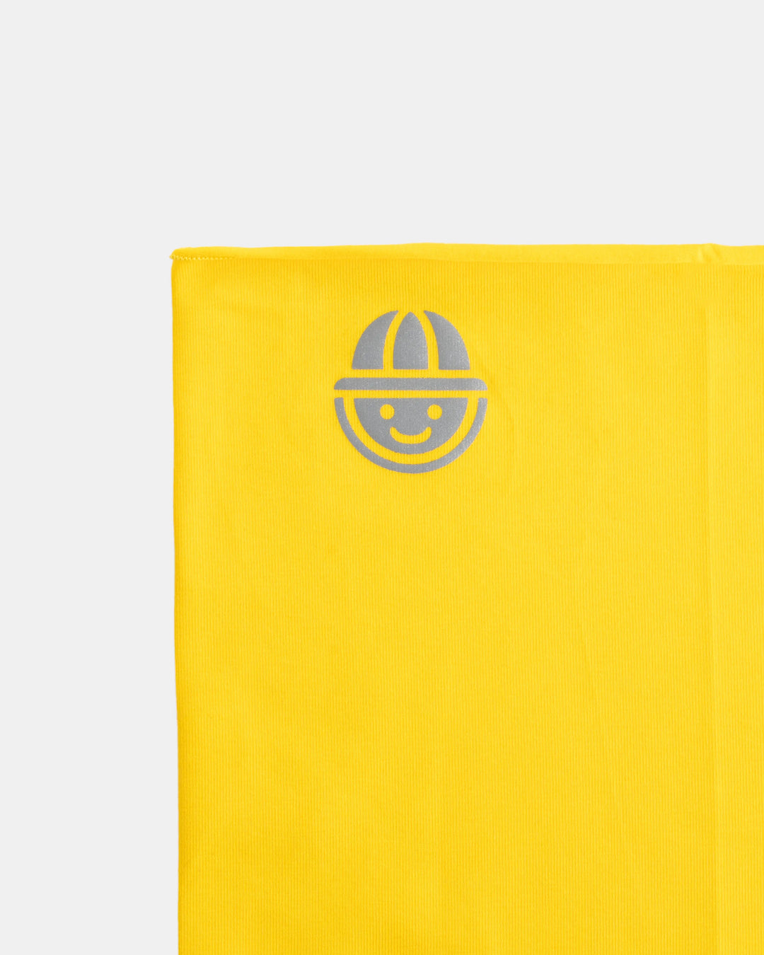Close-up of reflective logo on yellow organic cotton tubular scarf (neck warmer) from the Vivid collection