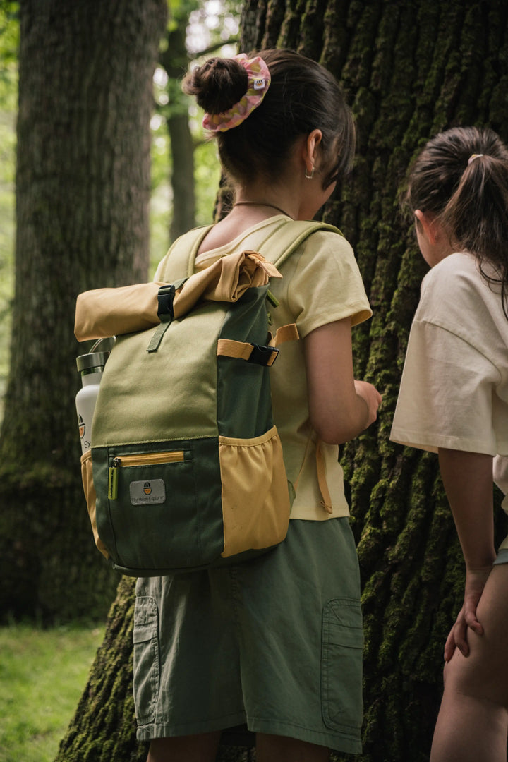 Two girls wearing Maju recycled polyester backpacks exploring a tree trunk